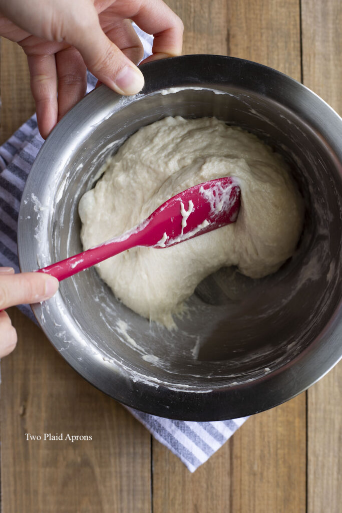 Mixing the ingredient for the hotteok dough in a bowl with a rubber spatula.