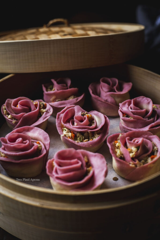 Side view of a steam basket full of vegetarian rose shaped dumplings.
