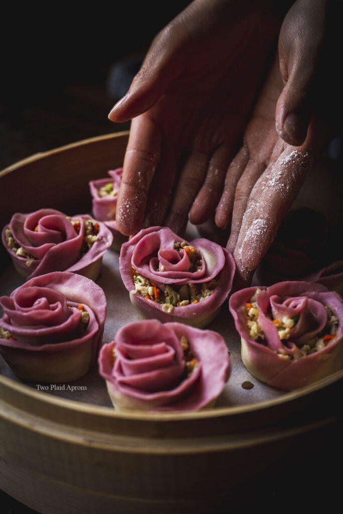 Placing a rose shaped dumpling into the bamboo steamer.