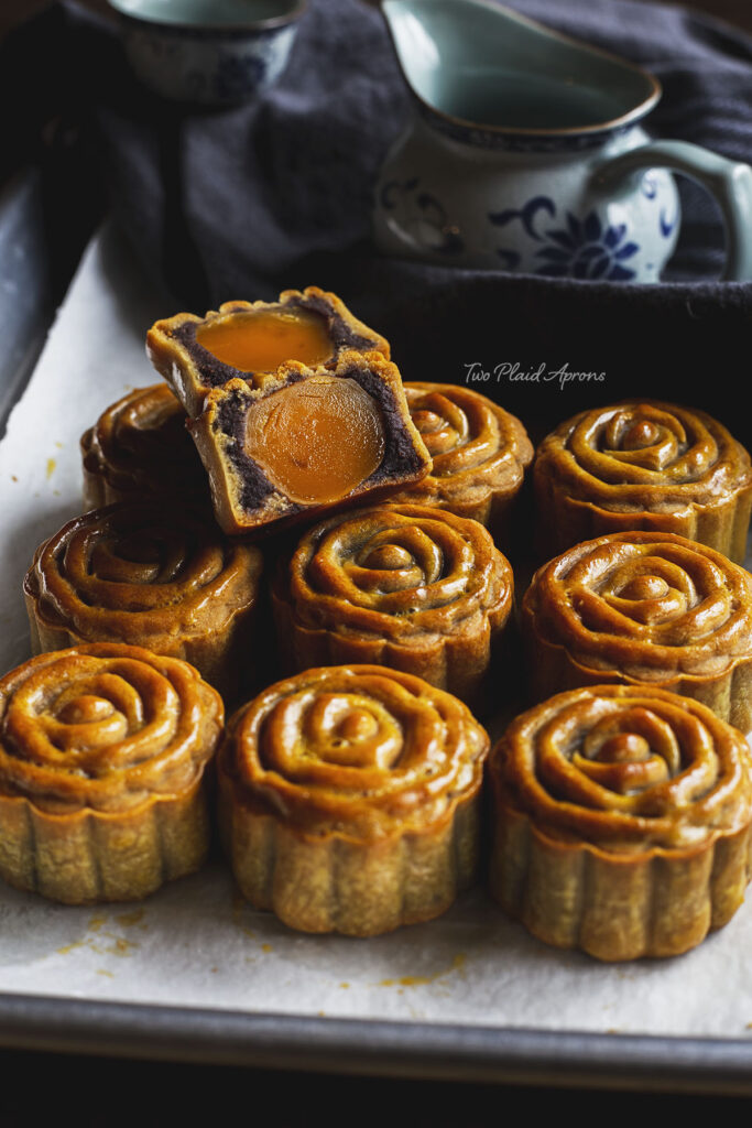 Front angled view of mooncakes on a tray with one cut open.