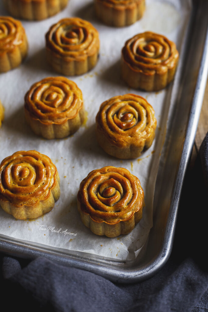 Top angled view of baked mooncakes on a tray.