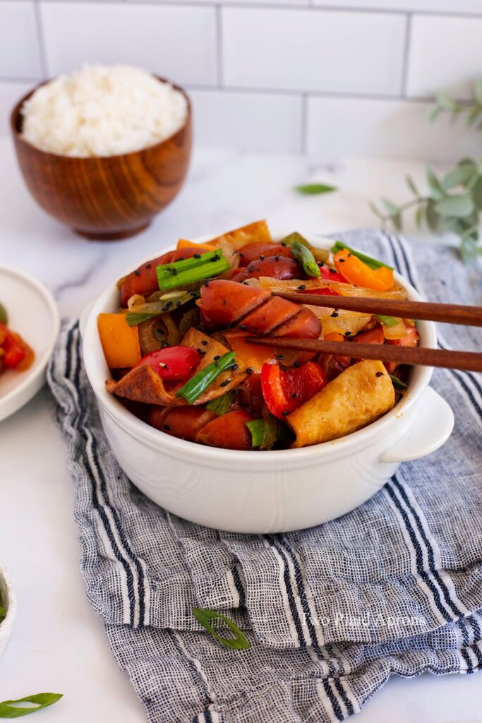 Close up view of picking up a sausage from the Korean sausage stir fry.