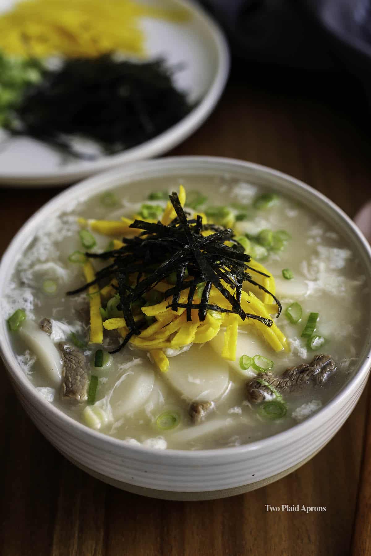 Close up of tteok guk in a bowl with garnish.