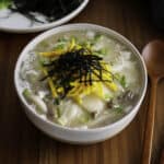 Dduk guk garnished with egg, green onion, and seaweed strips.
