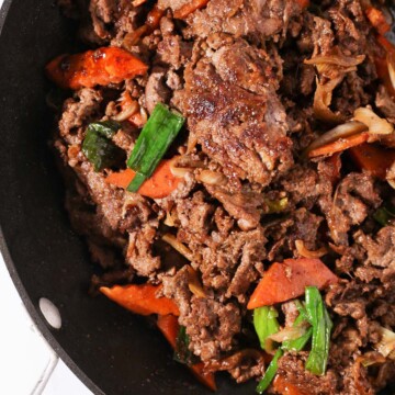 Top down view of Korean beef bulgogi with vegetables in a pan.