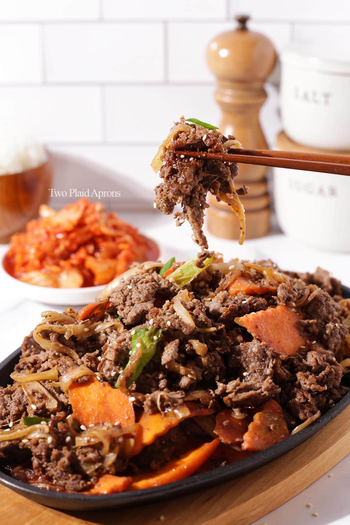 Korean beef bulgogi with vegetables and served on a cast iron plate.
