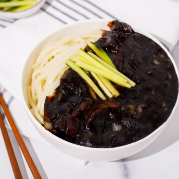 A bowl of jajangmyeon garnished with cucumbers.