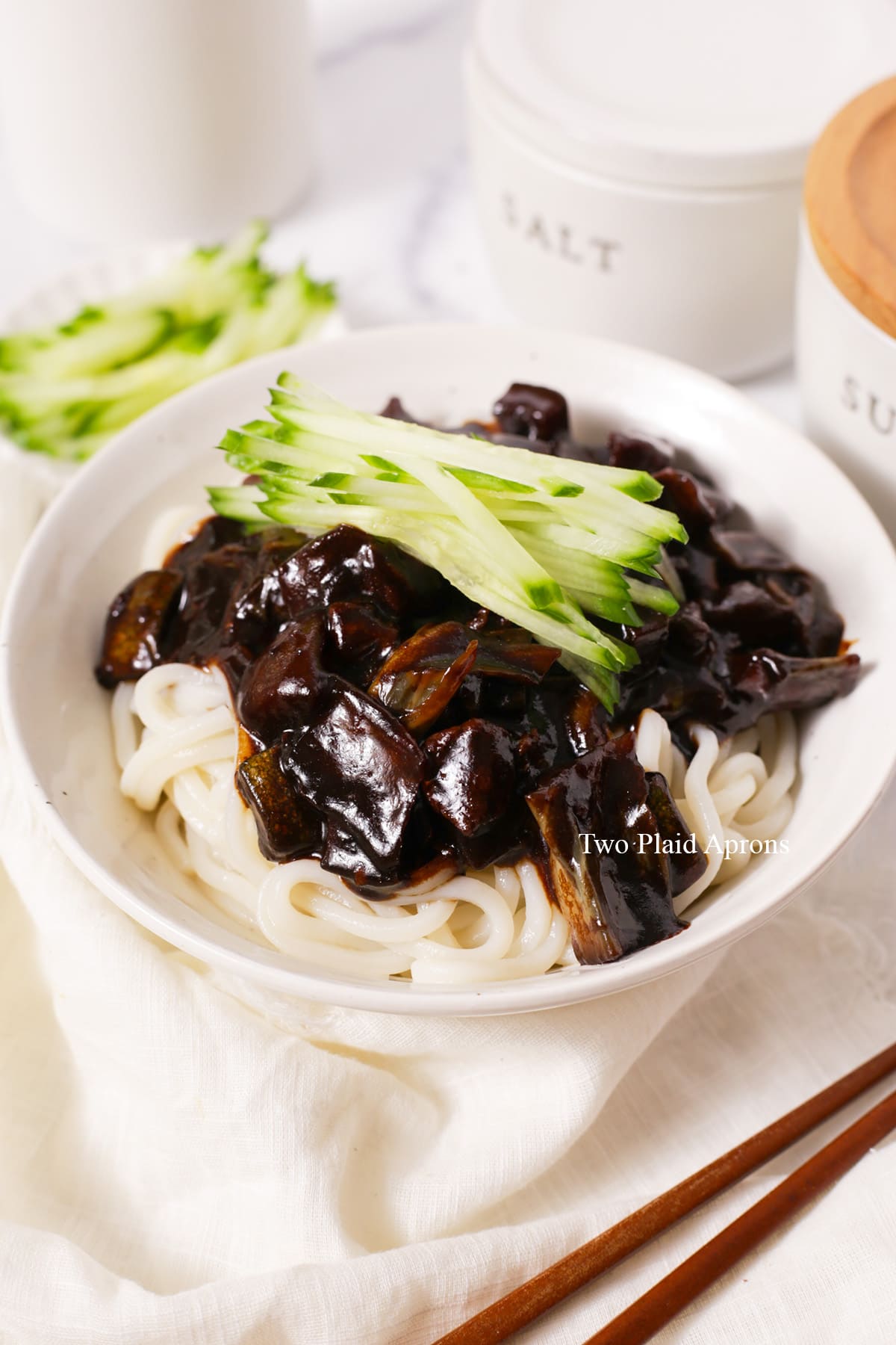 A bowl of Korean black bean noodles garnished with julienned cucumber.