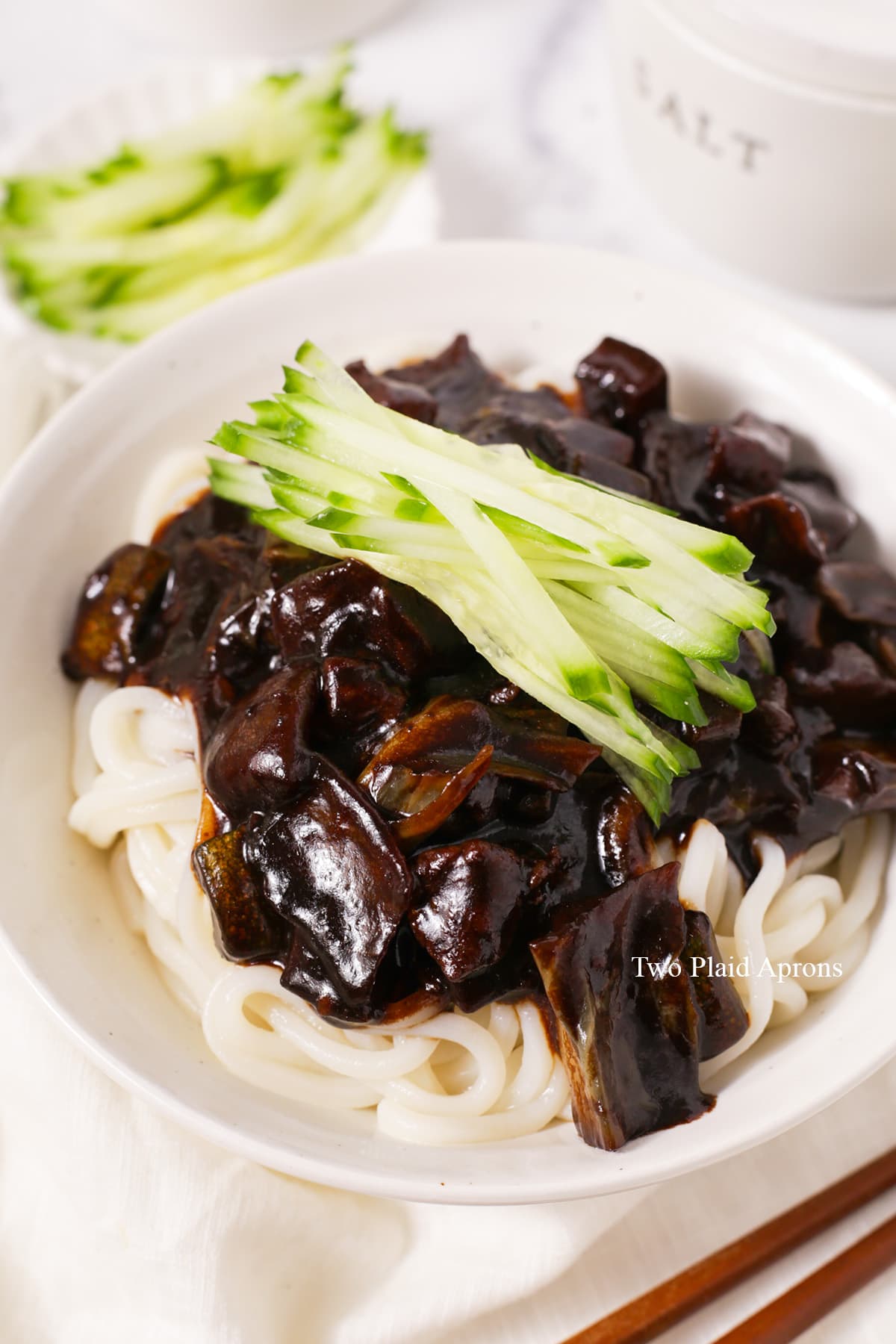 Close up view of a bowl of Korean black bean noodles with julienned cucumbers.