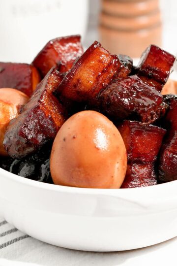 Hong shao rough with boiled eggs in a white bowl.