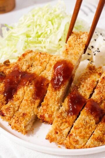 Picking up a piece of air fried chicken katsu with chopsticks.