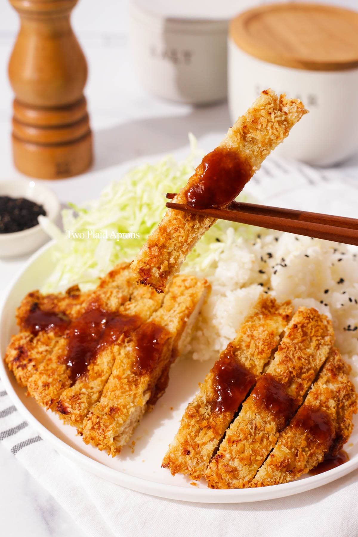 Holding air fryer chicken katsu with chopsticks.