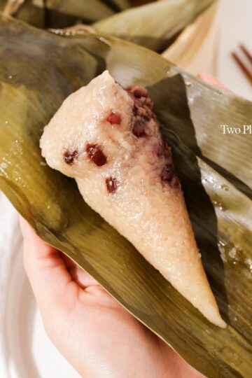 Holding an unwrapped zongzi with red beans.