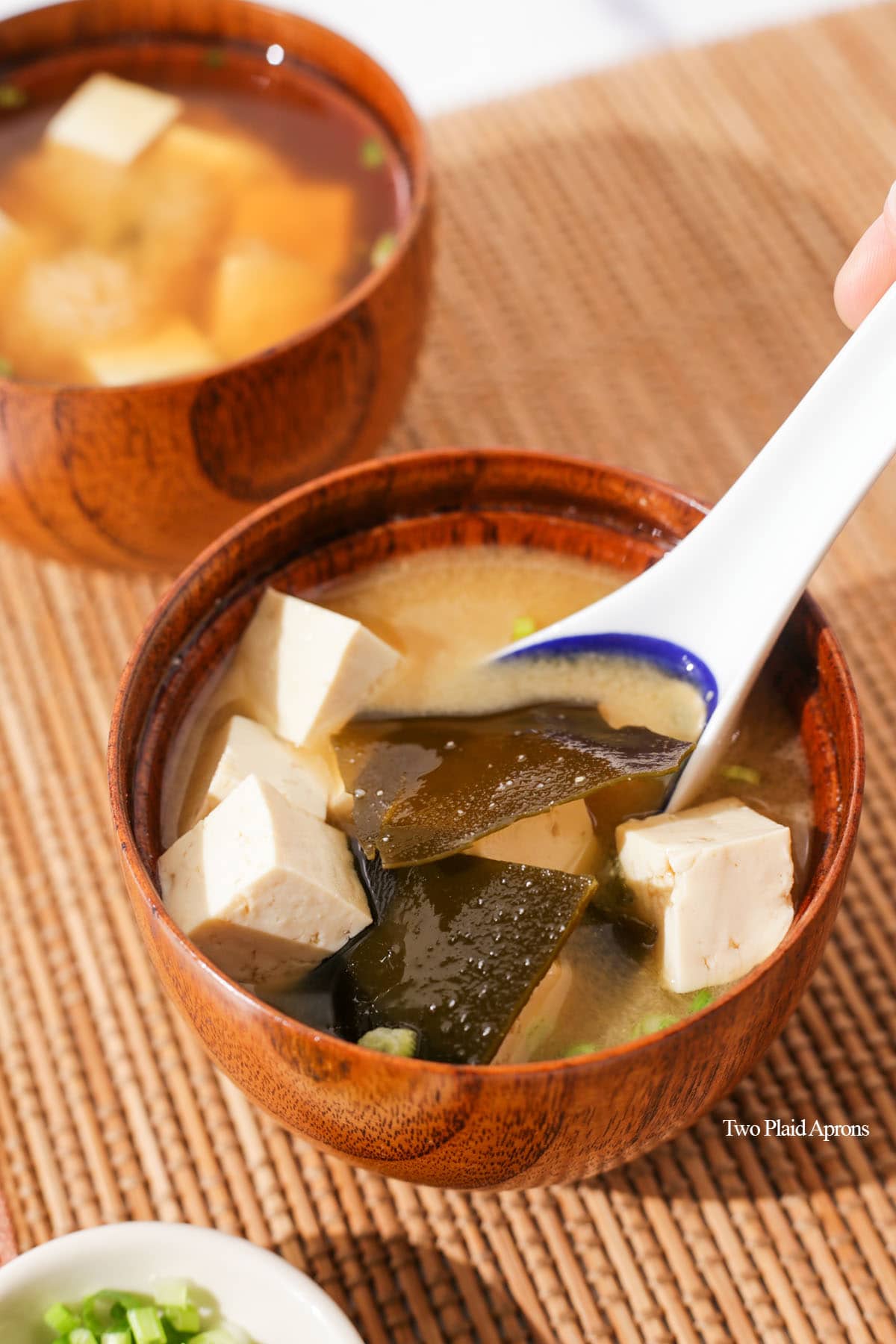Stirring a bowl of miso soup with tofu and seaweed.