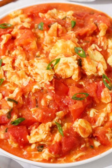 Tomato egg stir fry garnished with green onions.