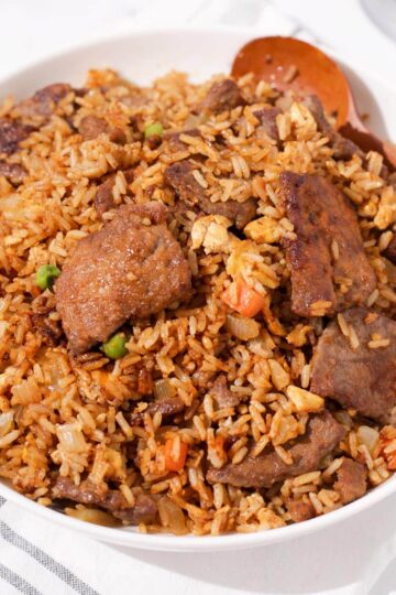 A bowl of beef fried rice with sha cha sauce.