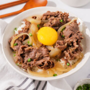 A bowl of gyudon topped with an egg yolk.