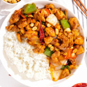 Top down view of a plate of kung pao chicken with rice.