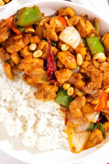 Top down view of a plate of kung pao chicken with rice.