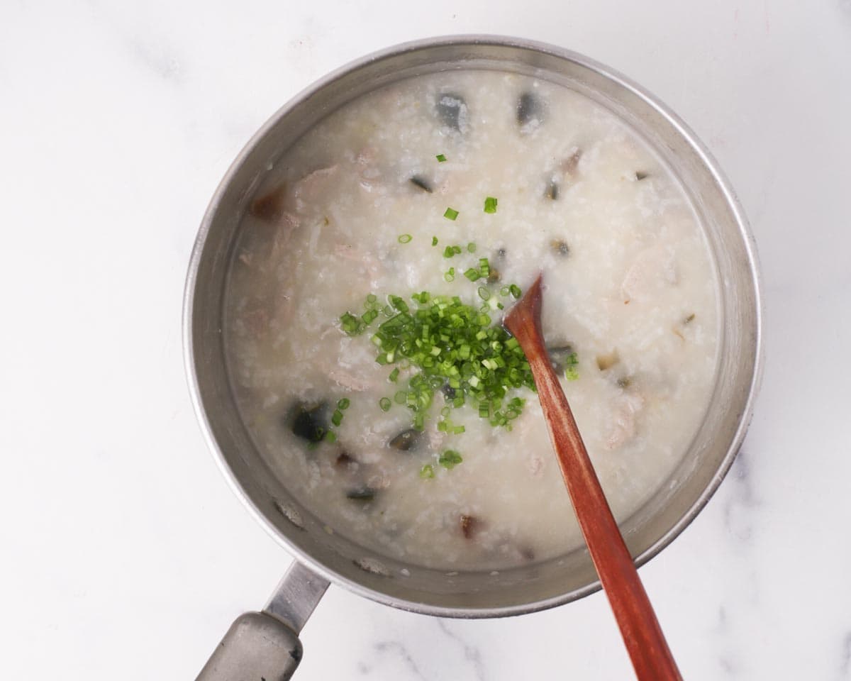 Adding green onions to the congee.