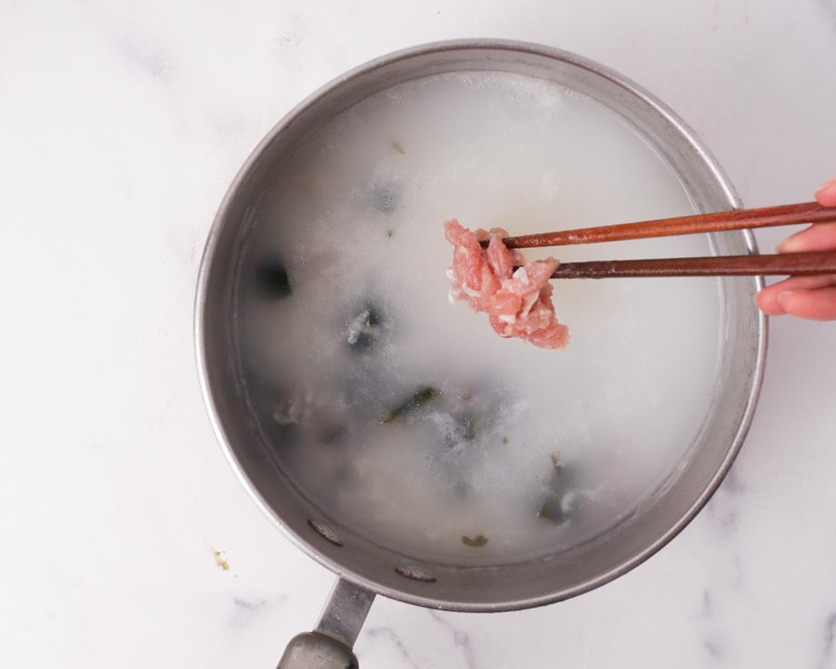 Adding pork into the congee.