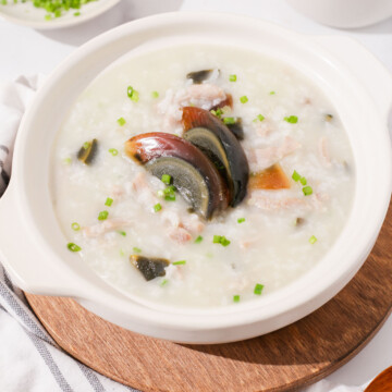 Side shot of century egg and pork congee in claypot thumbnail.