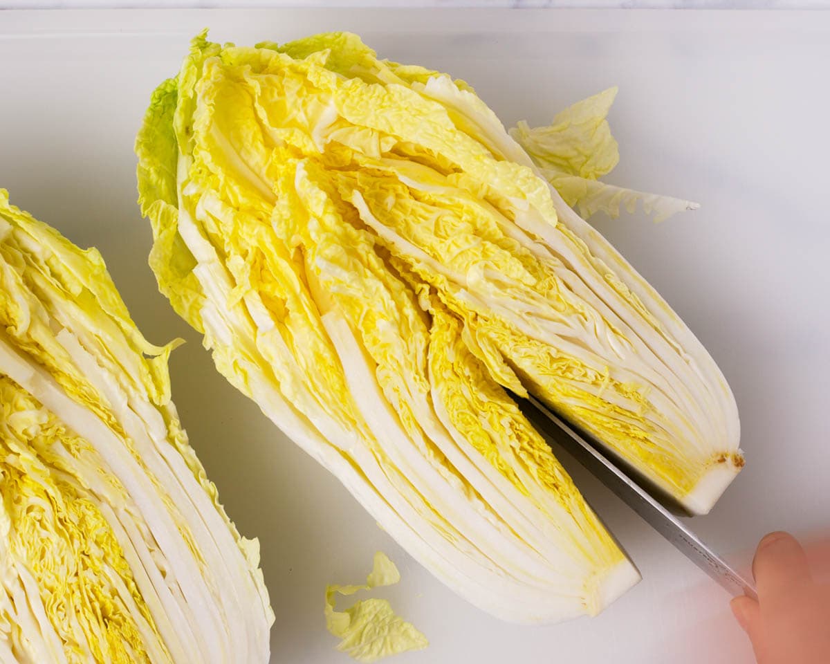 Cutting halved napa cabbage mid way.