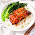 A plate of miso salmon with rice and green vegetables.