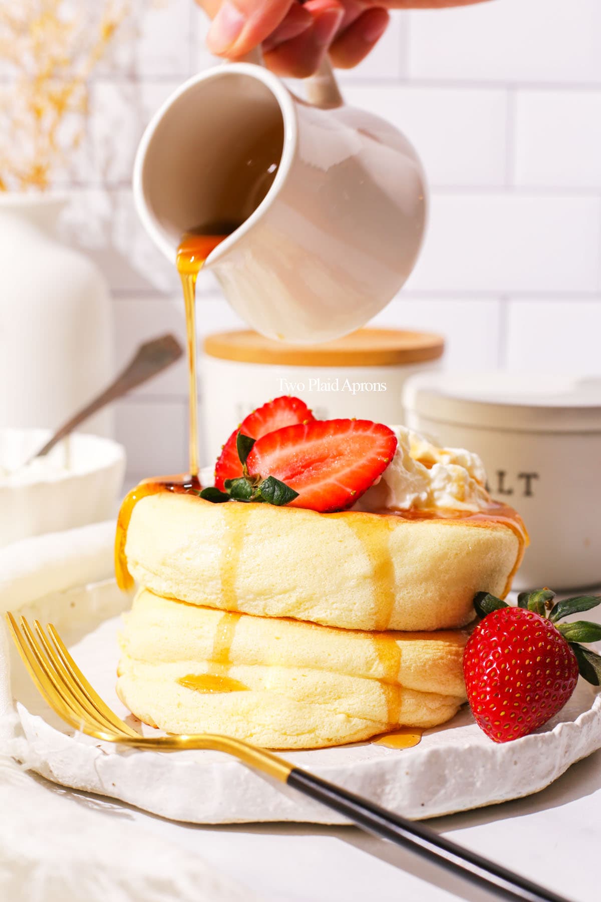 Pouring maple syrup onto a stack of Japanese soufflé pancakes.