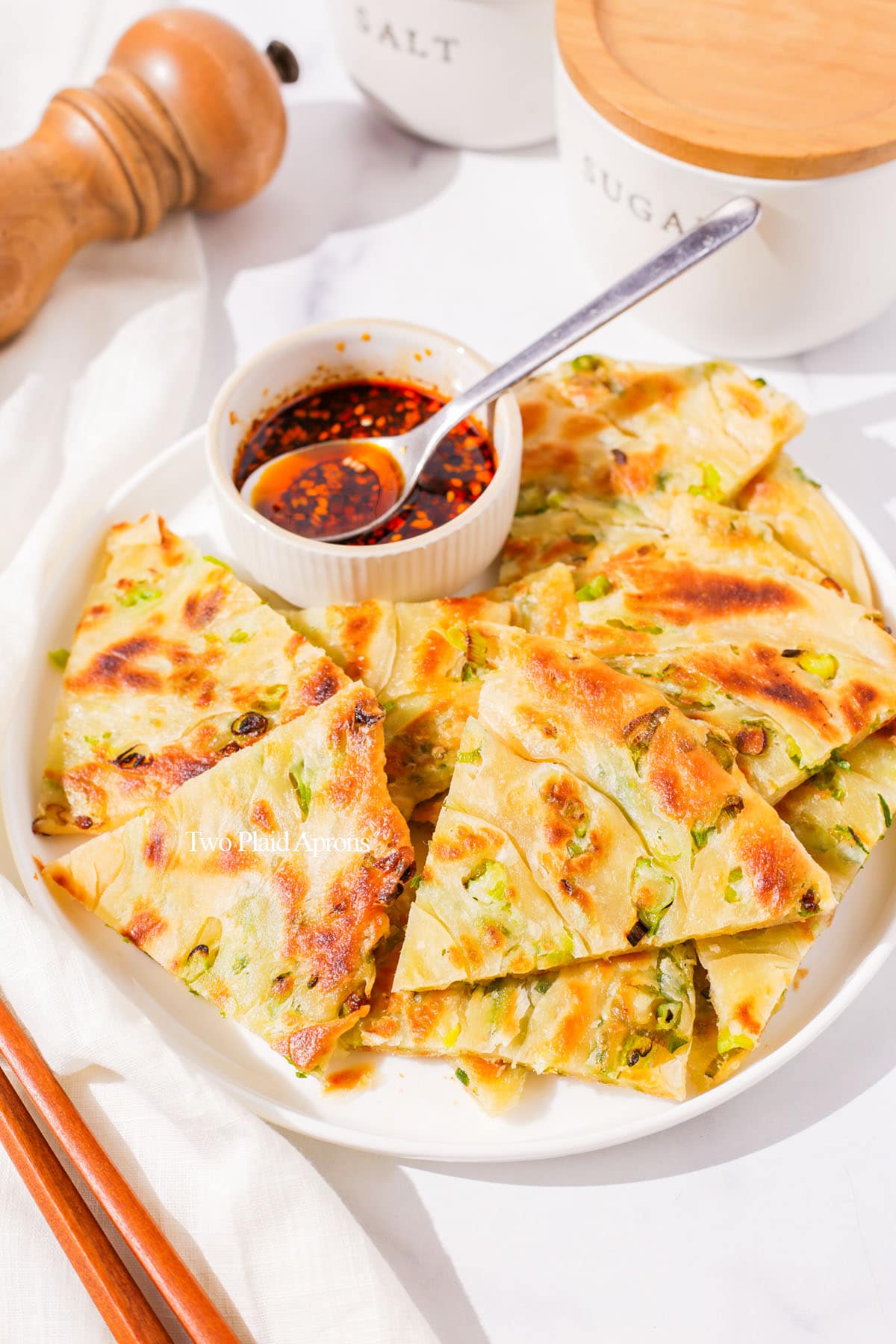 Scallion pancake on plate with dipping sauce.