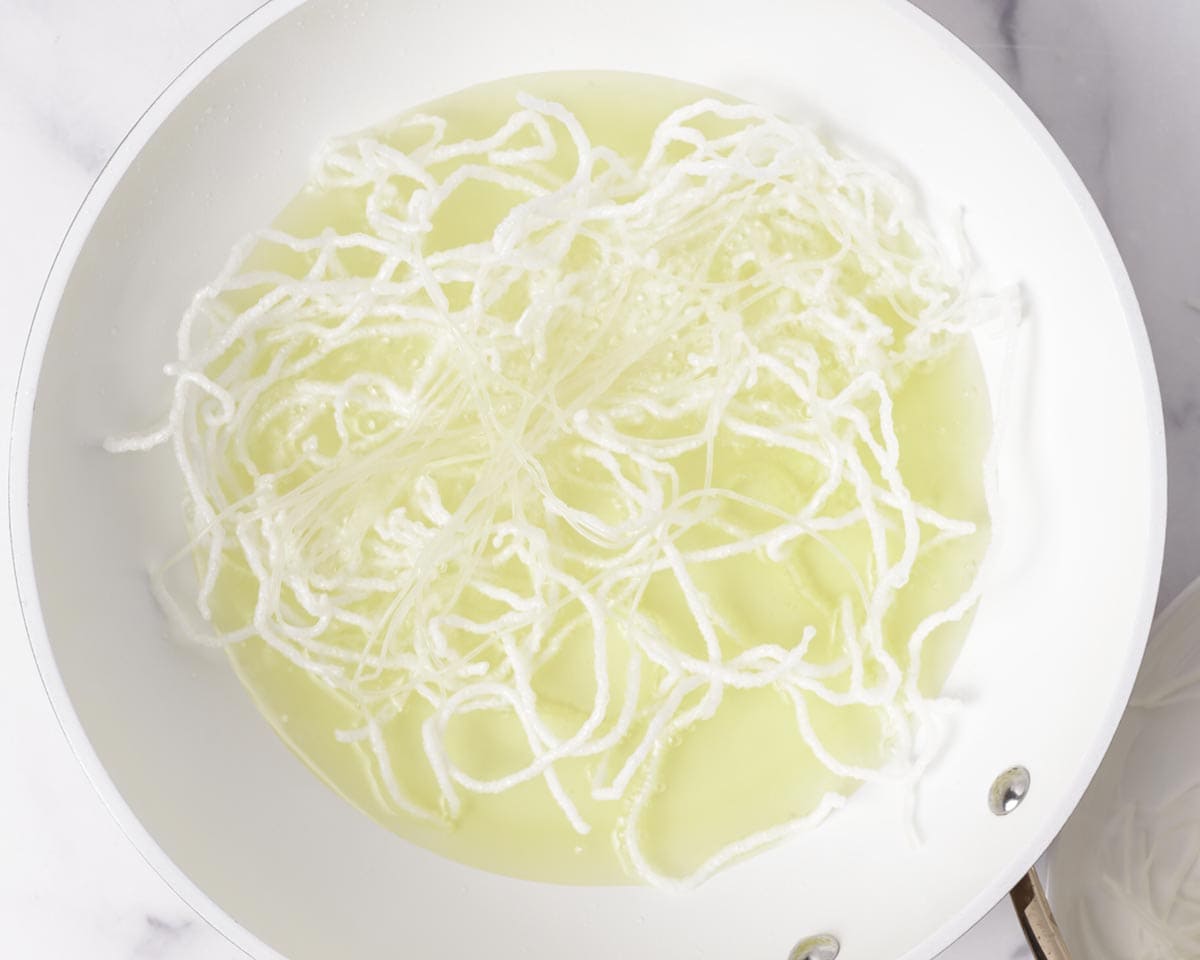 Frying rice vermicelli noodles in a pan of oil.