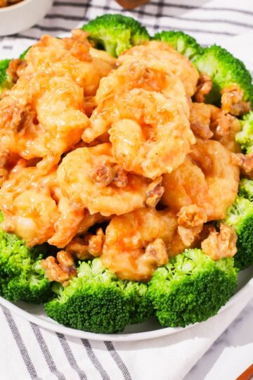 A plate of honey walnut shrimps garnished with broccoli.