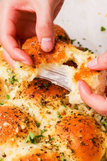 Tearing a Christmas tree bread roll to show cheese pull.
