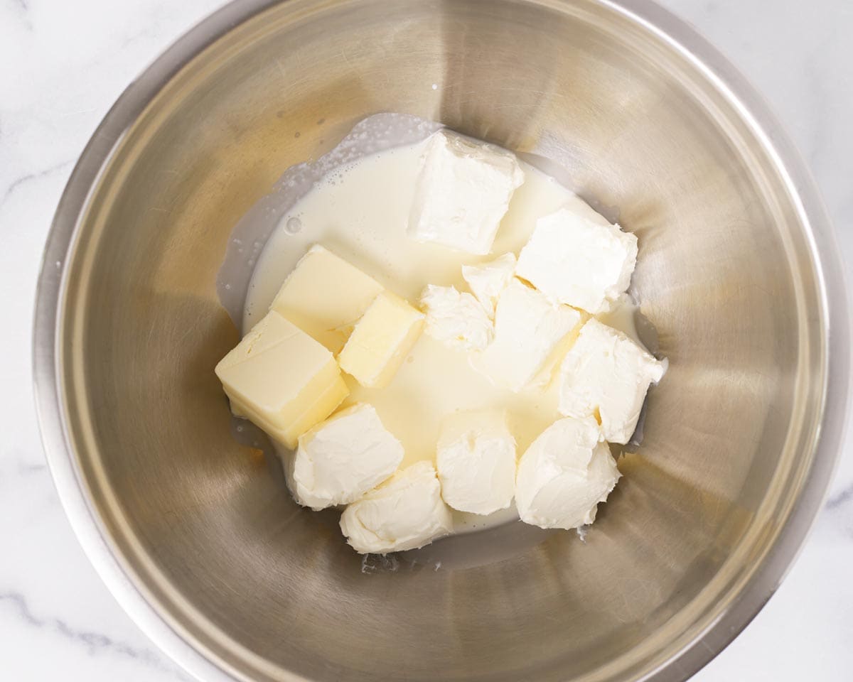 Adding cream cheese butter and heavy cream into a mixing bowl.