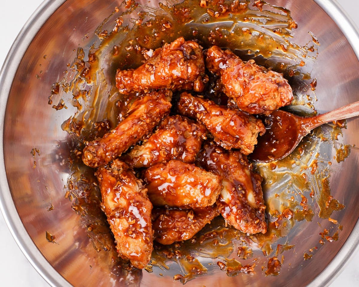 Mixing the Korean fried chicken wings with soy garlic sauce.
