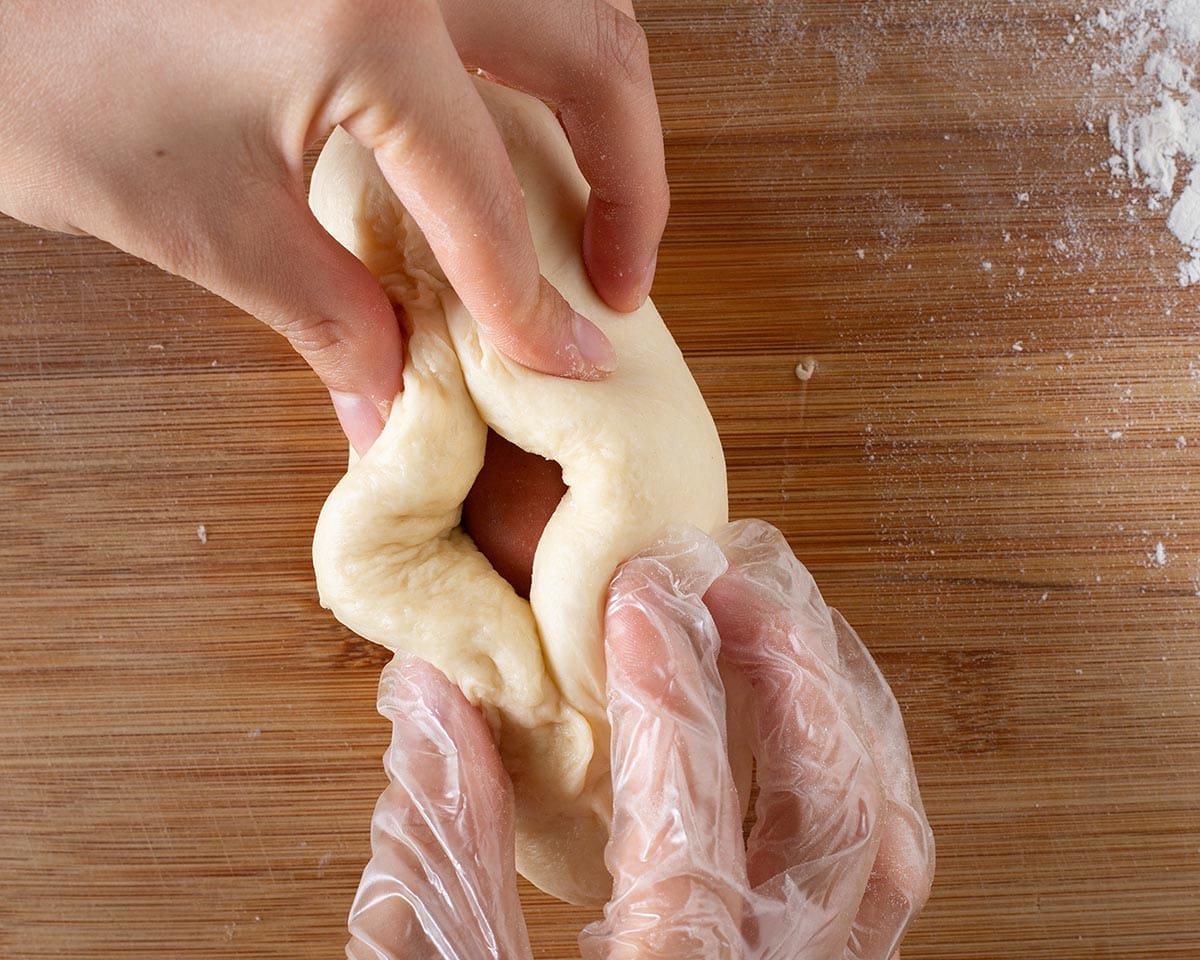 Closing the dough around the hotdog.