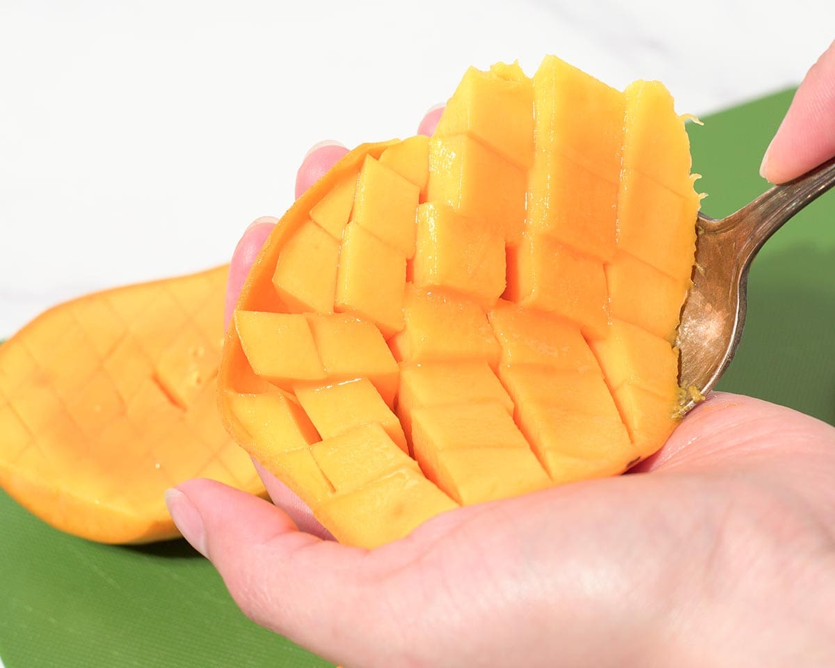Using spoon to scoop our cubed mango.