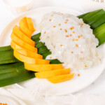 Mango sticky rice on a plate with pandan leaf, thumbnail shot.