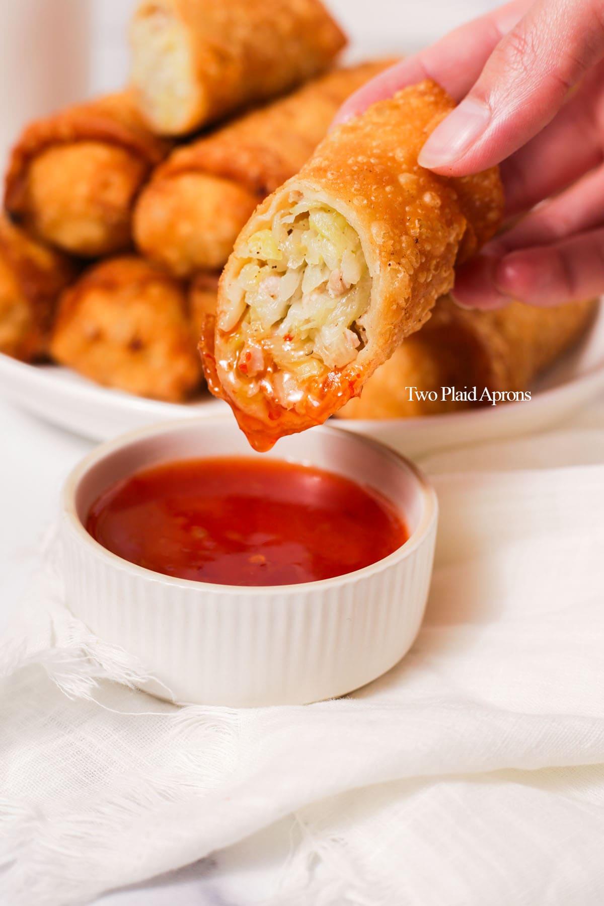 Chinese egg rolls dipped in sweet and sour sauce.