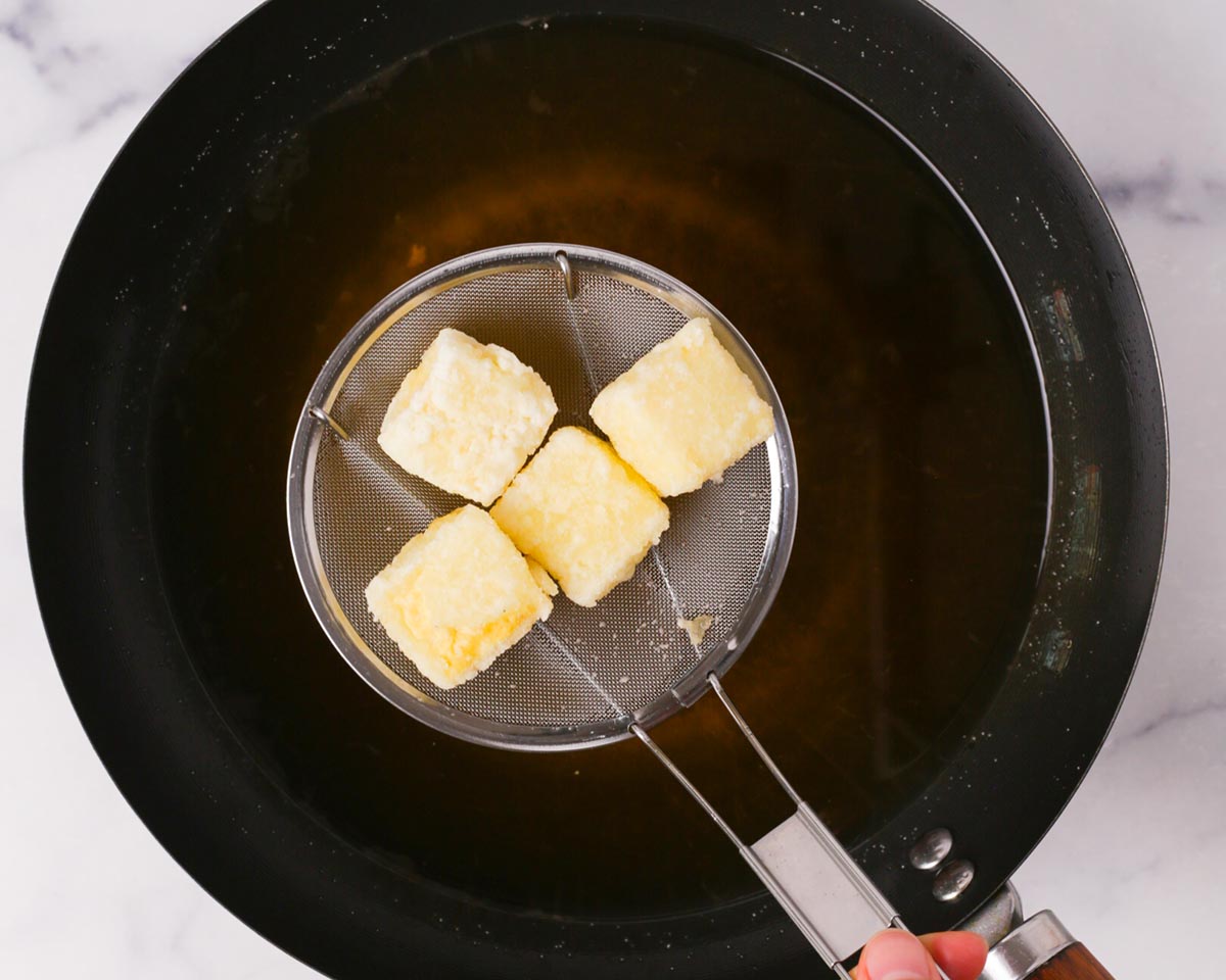 Frying the tofu until crispy.