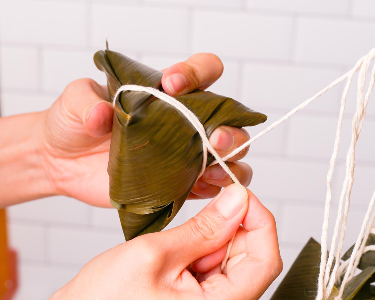 Going around the zongzi with the string twice.