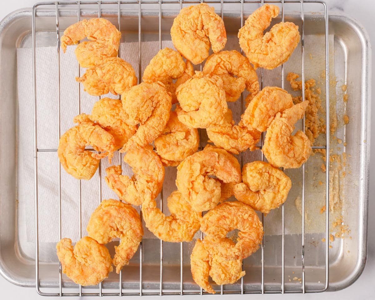 Placing the fried shrimps onto a rack to drain.