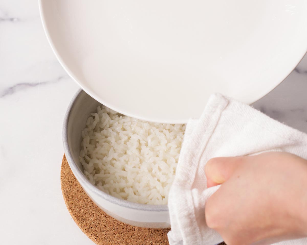 Pouring the water back into the bowl with rice.