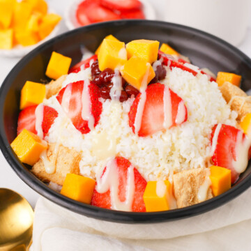 Bingsu in a bowl with different toppings and condensed milk.