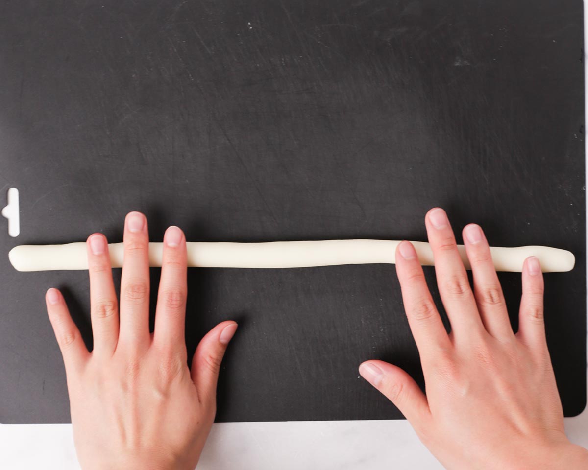 Rolling a piece of potato dough into a thick noodle.