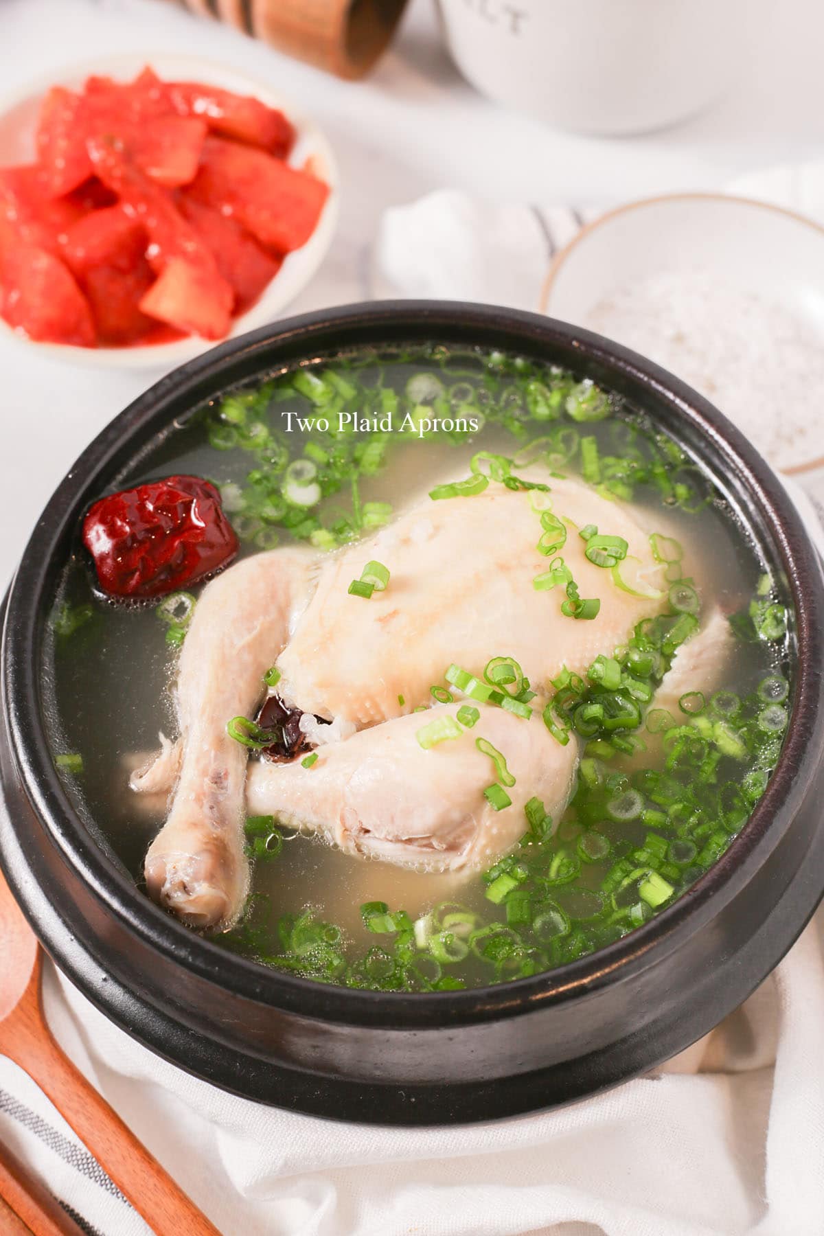 A bowl of samgyetang loaded with green onions.