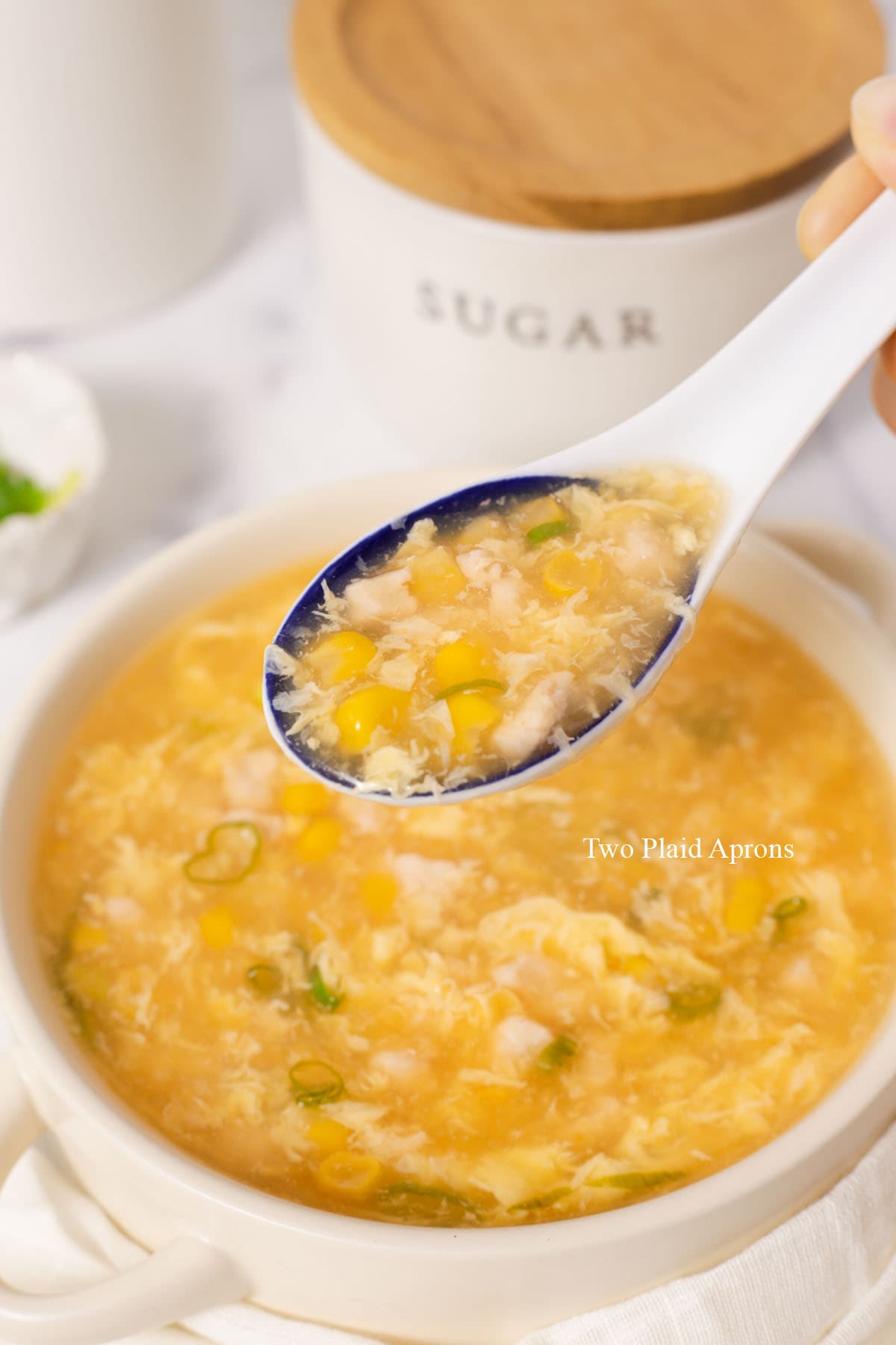 Spoon with chicken and corn soup.