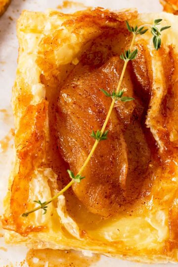 An upside down apple tart garnished with thyme.