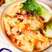 A bowl of wonton noodle soup with chili oil.