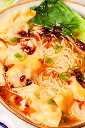 A bowl of wonton noodle soup with chili oil.